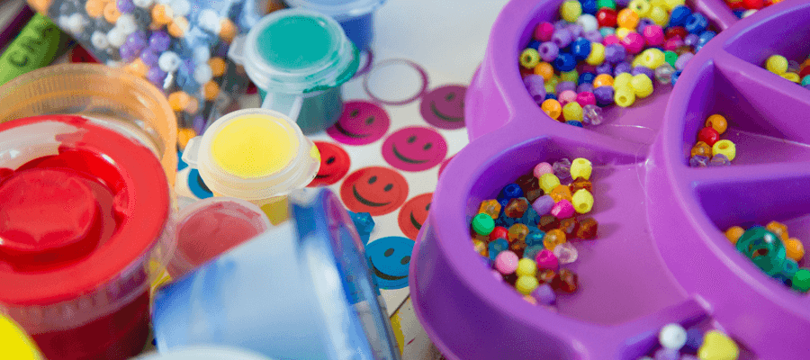 colored beads and crafting paints in a tray